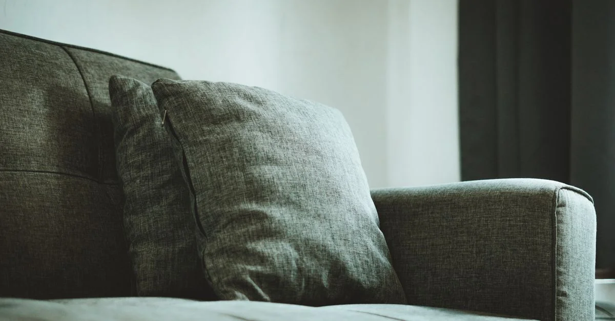 Gros plan d'un canapé gris moderne avec des coussins moelleux, créant une ambiance chaleureuse dans une maison de Jakarta.