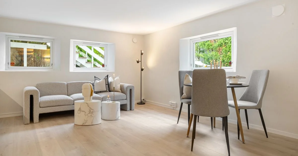 Salon contemporain avec un canapé gris, un coin repas et un revêtement de sol en bois.