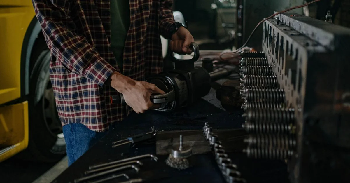 Mécanicien utilisant des outils dans un atelier de réparation automobile pour l'entretien des véhicules.